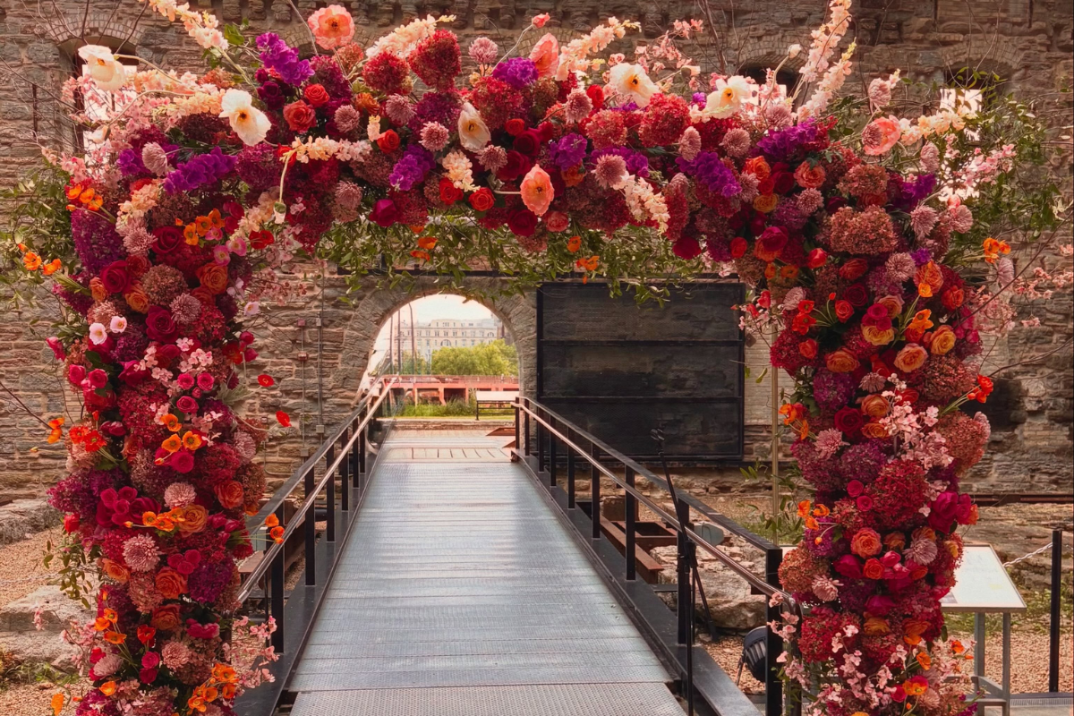 Vibrant pink, orange and coral wedding floral arch at an off-site venue, designed by Camrose Hill Flower Studio