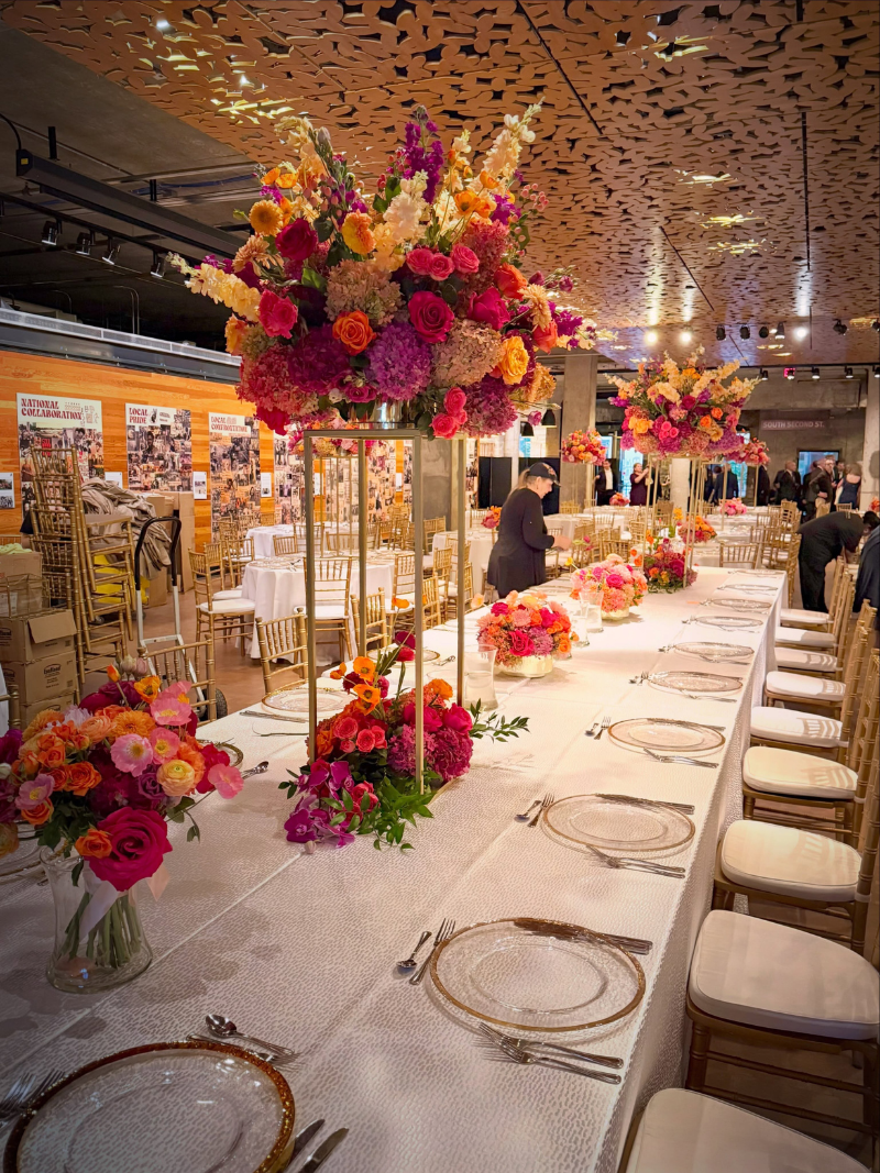 Off-site wedding reception tables decorated with vibrant pink, orange and coral floral centerpieces by Camrose Hill Flower Studio